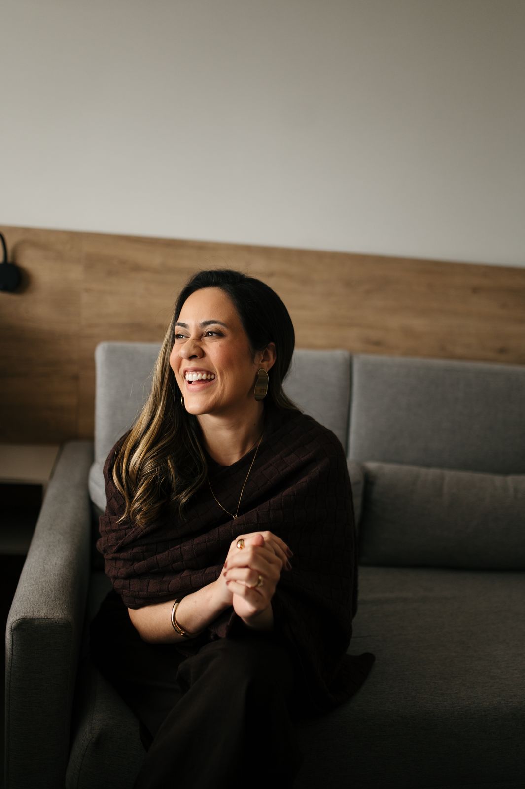 Luíza Sales sorrindo, sentada no sofá durante uma conversa